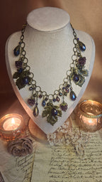 Halskette mit Weinlaub, violetten Lampwork-Himbeeren und blauen Kristalltropfen auf Schmuckbüste