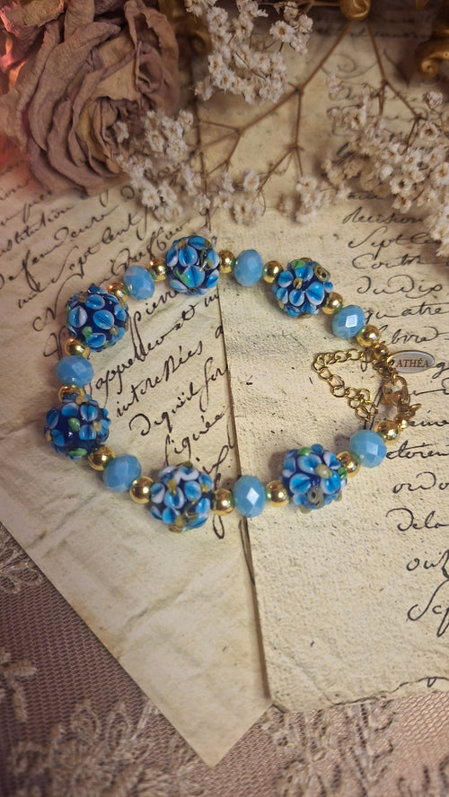 Armband mit dunkelblauen Lampwork-Blütenperlen und himmelblauen Glasperlen auf antikem Brief